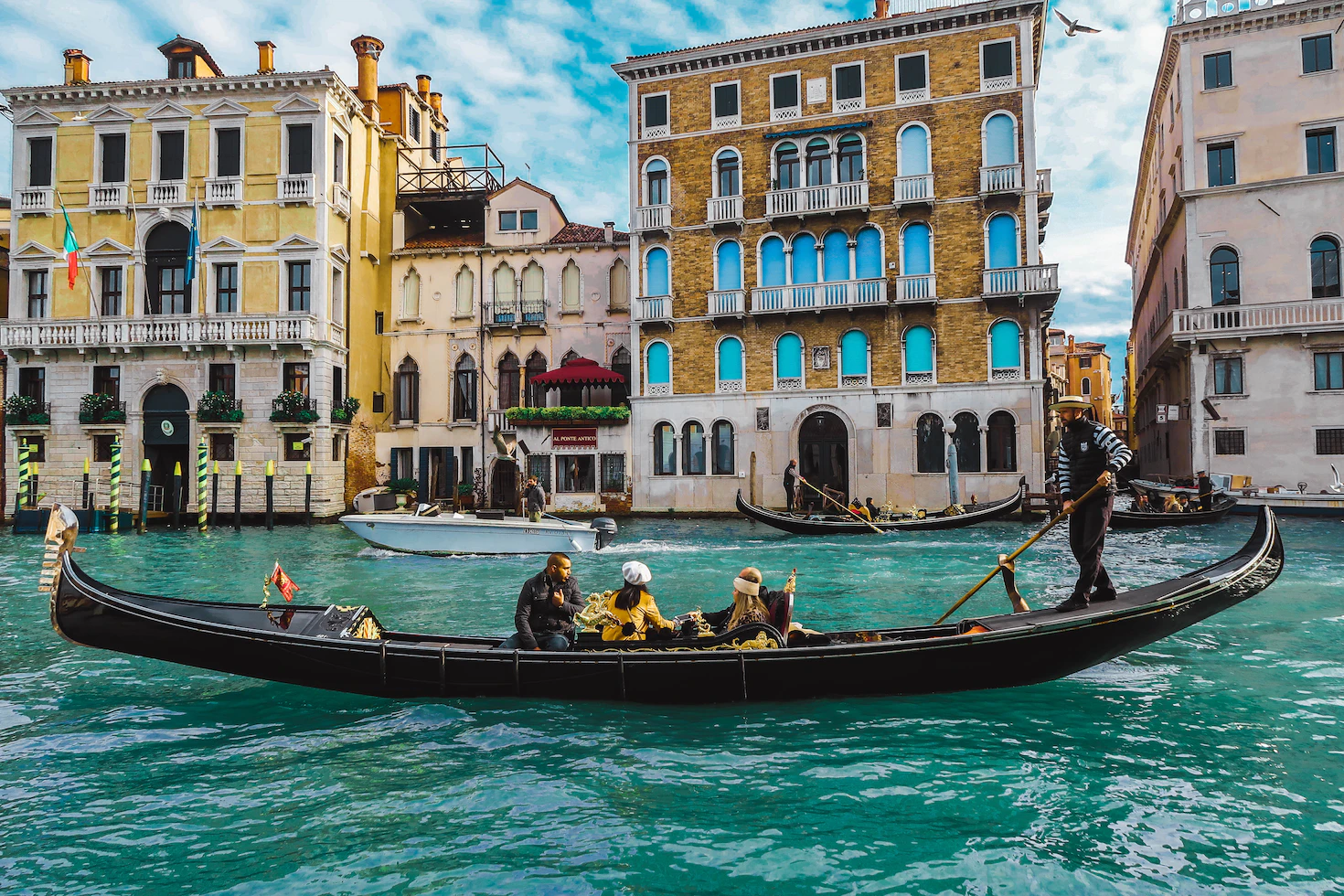 Gondola carrying passengers on the Grand Canal in front of colourful Venetian palaces