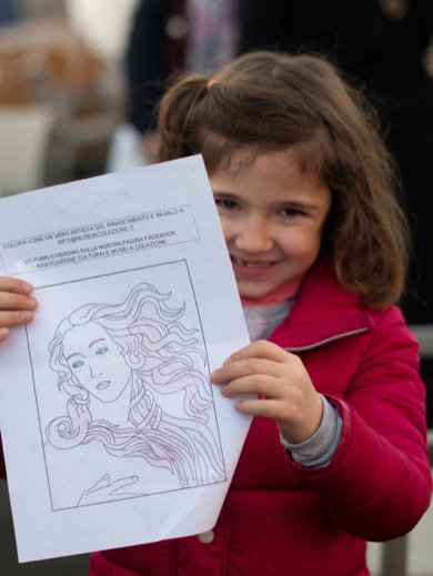 Smiling girl in a red jacket holding up a colouring sheet of a Renaissance painting