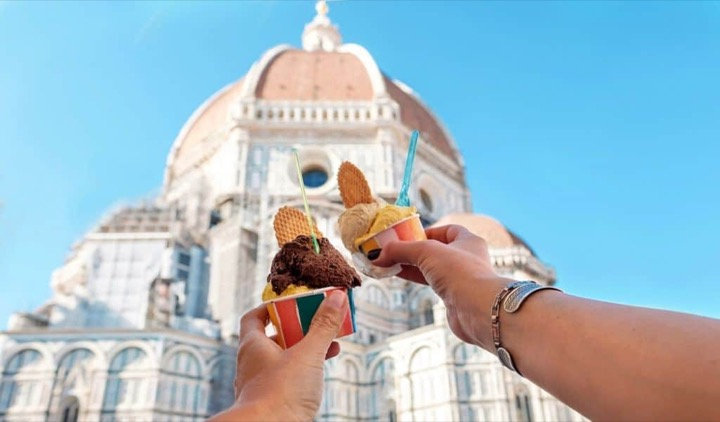Two gelato cups held up against the dome of Florence Cathedral and a blue sky