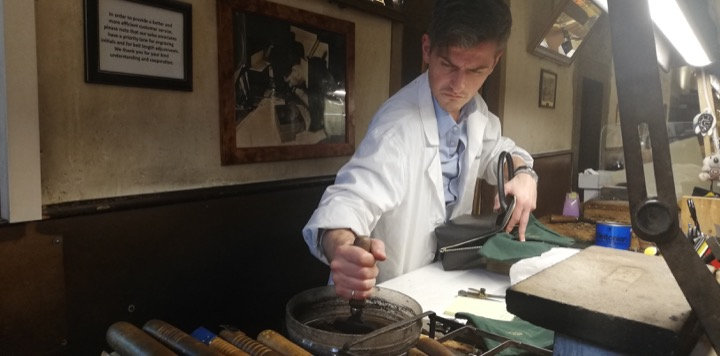Artisan in a white coat working at a bench in a Florentine workshop