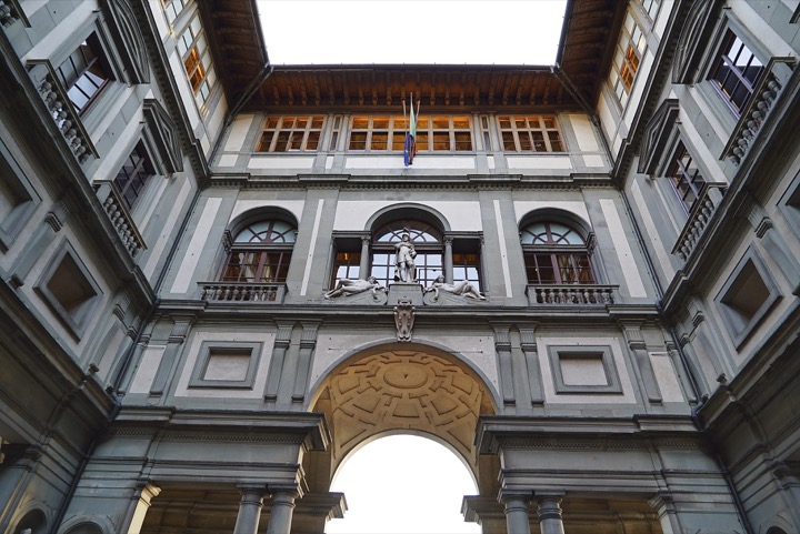 Looking up at an arched passage and Renaissance facades around a Florentine courtyard