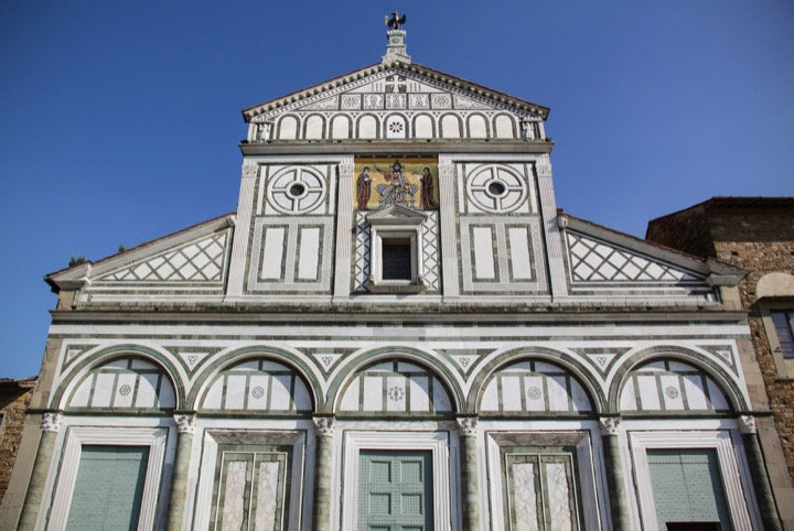 Marble facade of San Miniato al Monte with geometric green and white patterns and a golden mosaic