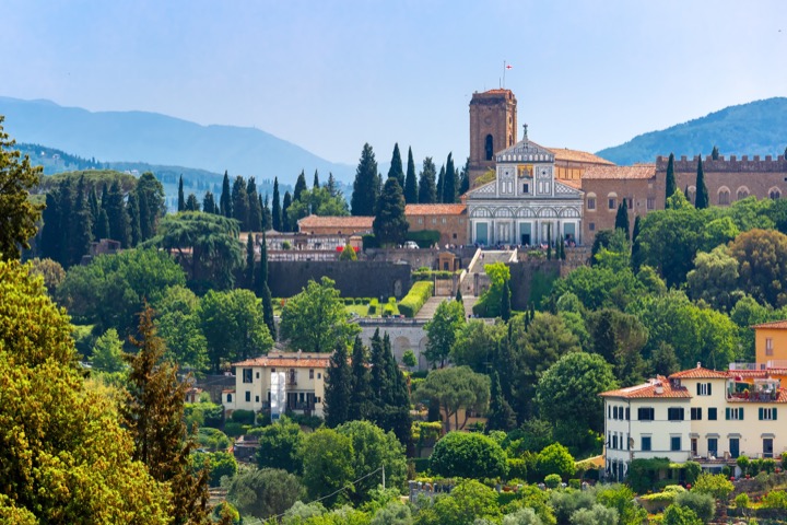 San Miniato al Monte and its bell tower among cypresses and green hillside above Florence