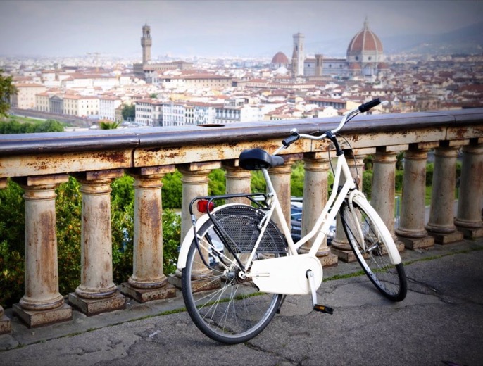 White city bicycle parked at a stone balustrade, with the Duomo and Florence's rooftops beyond