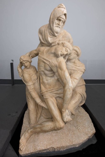 Marble Pietà sculpture of a hooded figure supporting the body of Christ, displayed in a museum