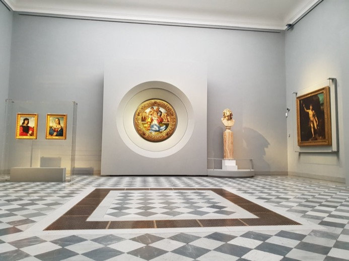 Uffizi room with Michelangelo's round Doni Tondo on the wall above a chequered marble floor