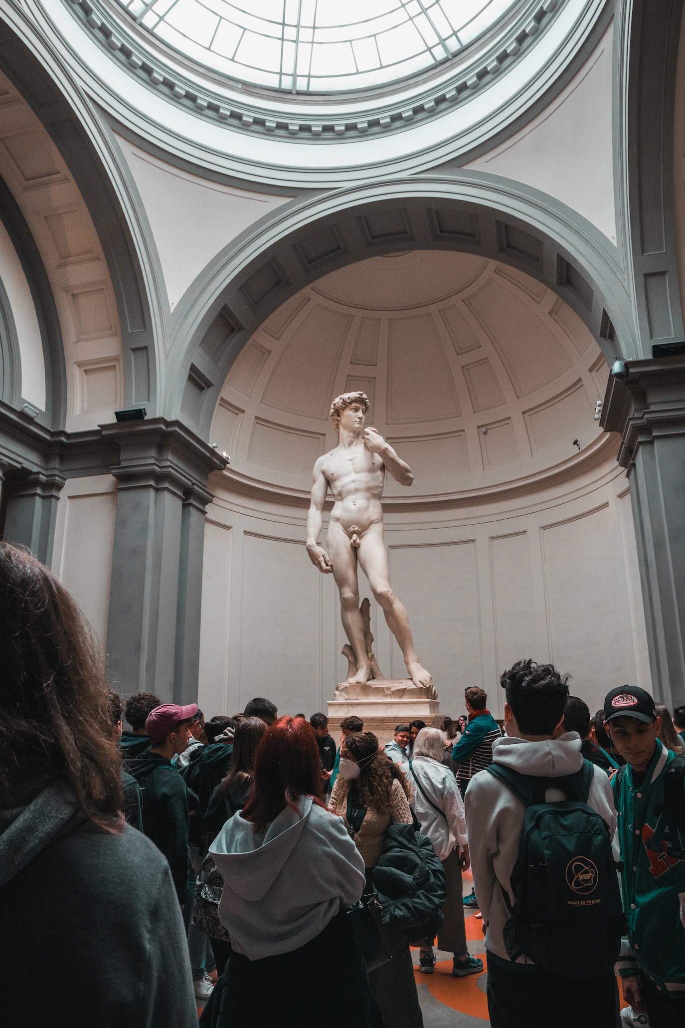 Visitors gathered beneath Michelangelo's David in the Tribune of the Accademia Gallery