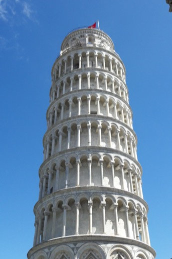 Looking up the Leaning Tower of Pisa against a deep blue sky