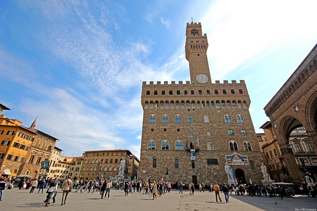 Palazzo Vecchio tower rising over Piazza della Signoria with visitors strolling below