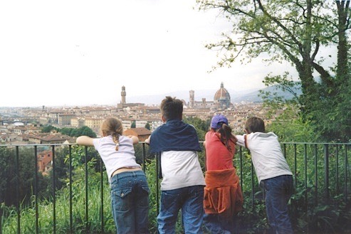 Four children leaning on a railing to look out over the rooftops and cathedral dome of Florence