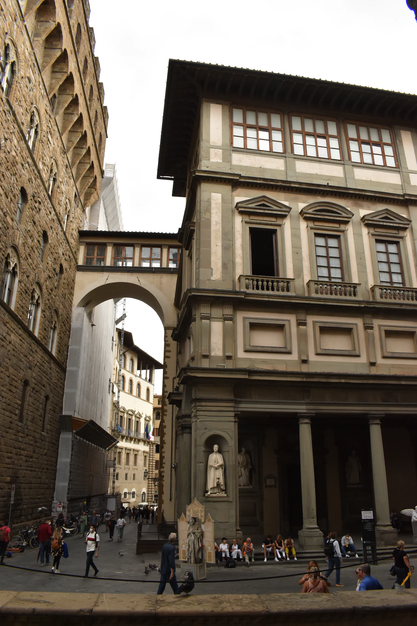 Uffizi's long arcade corner with a statue niche and a covered corridor arching overhead