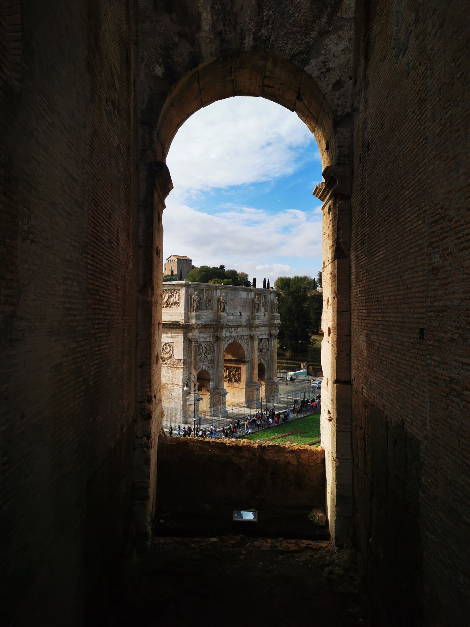 Arch of Constantine seen through a dark stone arch of the Colosseum
