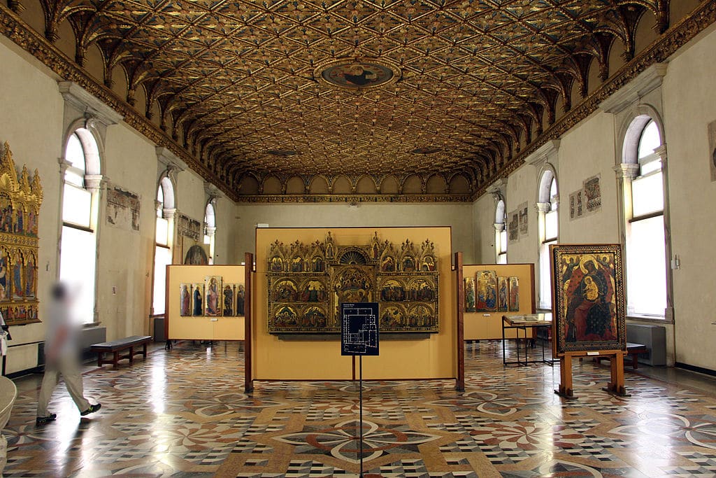 Gallery hall with a carved wooden ceiling, mosaic floor and gilded altarpieces on display