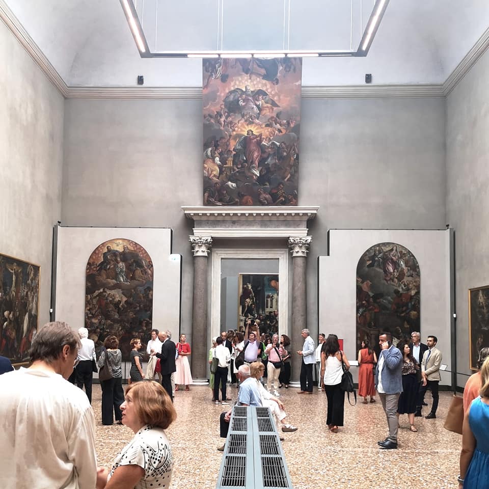 Visitors in a large gallery hall with huge Venetian altarpiece paintings on the walls