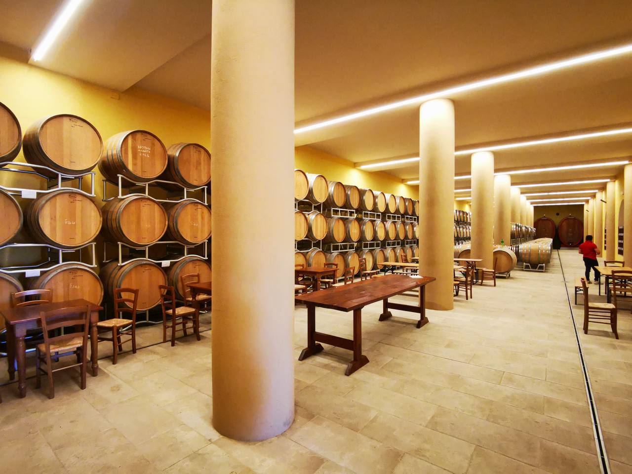Winery cellar with barrels along the walls and wooden tables set up for tasting