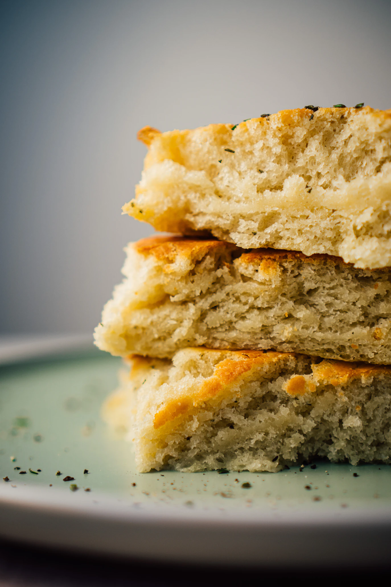 Stacked squares of golden focaccia on a pale green plate
