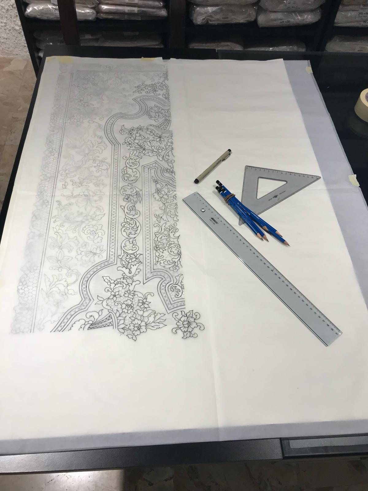 Delicate floral lace pattern drawn on tracing paper with a ruler, set square and pencils