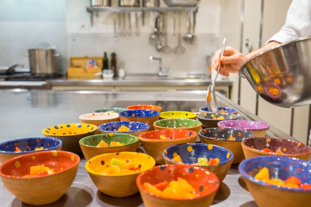 Colourful terracotta bowls filled with diced vegetables on a steel kitchen counter