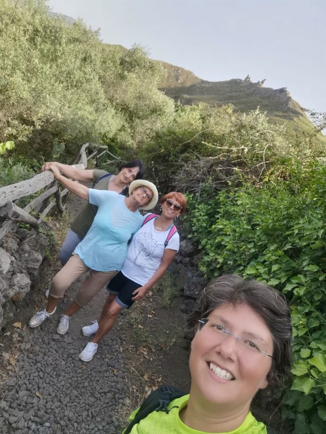 Group of hikers smiling in a selfie on a path lined with greenery