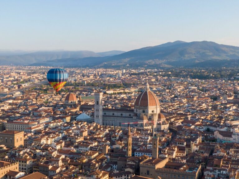 Hot air balloon drifting over the red rooftops and cathedral dome of Florence