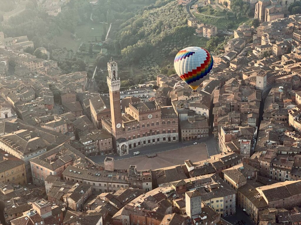 Hot air balloon beside the Torre del Mangia over Siena's Piazza del Campo