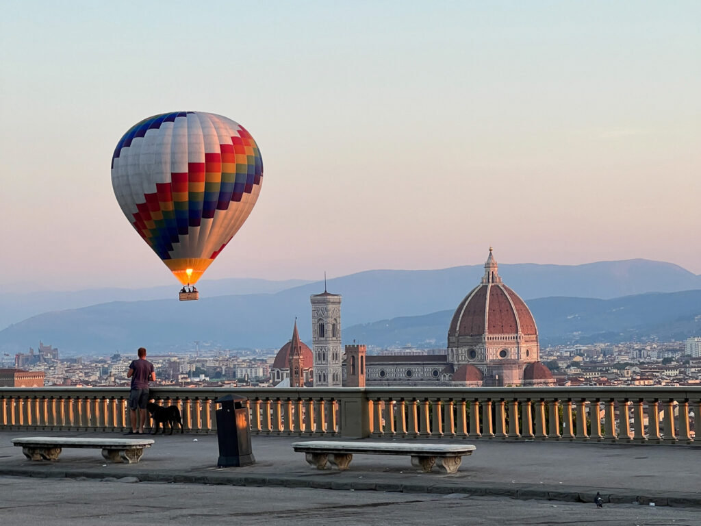 Hot air balloon at dawn above Florence skyline with the cathedral dome, seen from a panoramic terrace