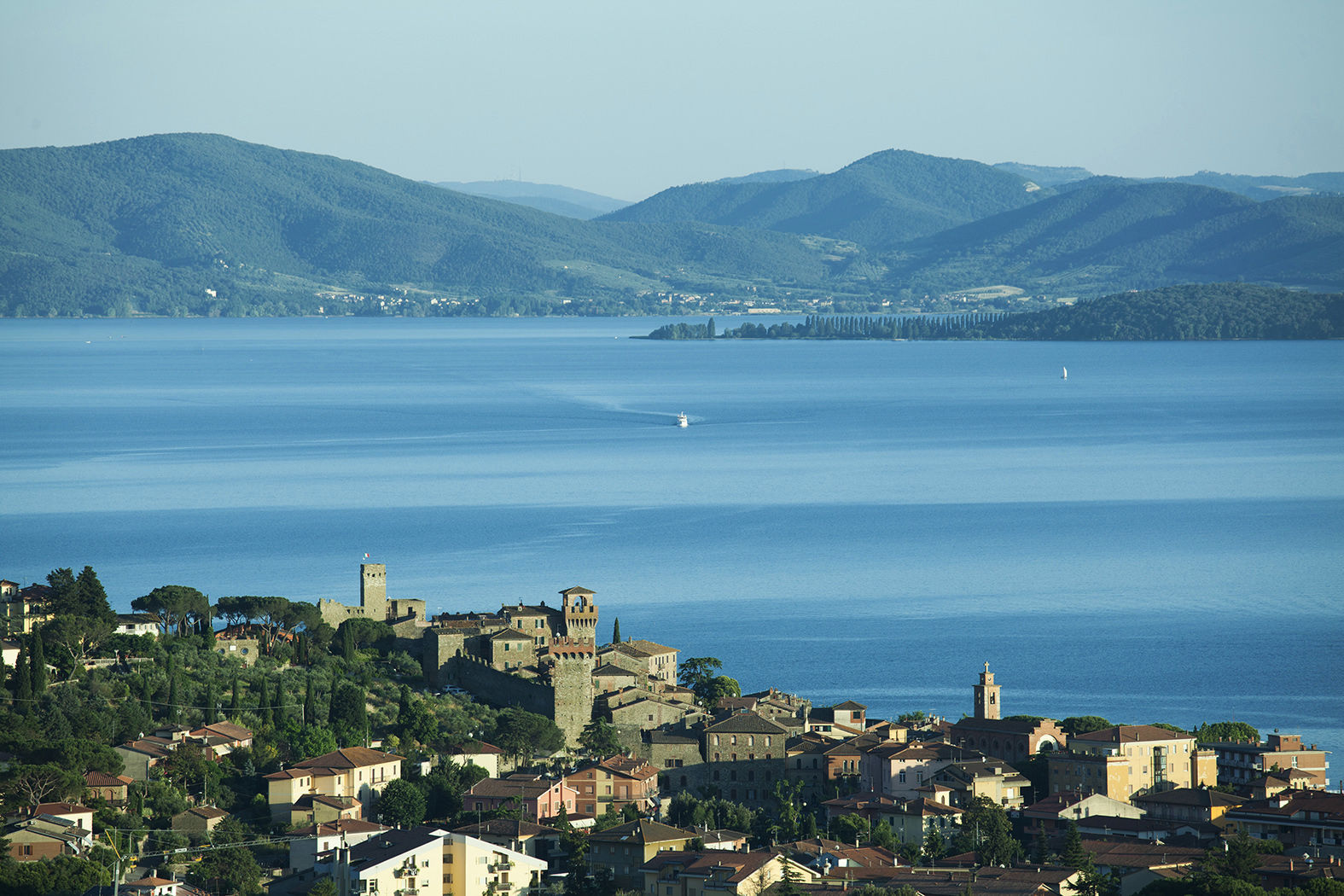 Lakeside town on a wooded hillside overlooking a wide blue lake and distant mountains