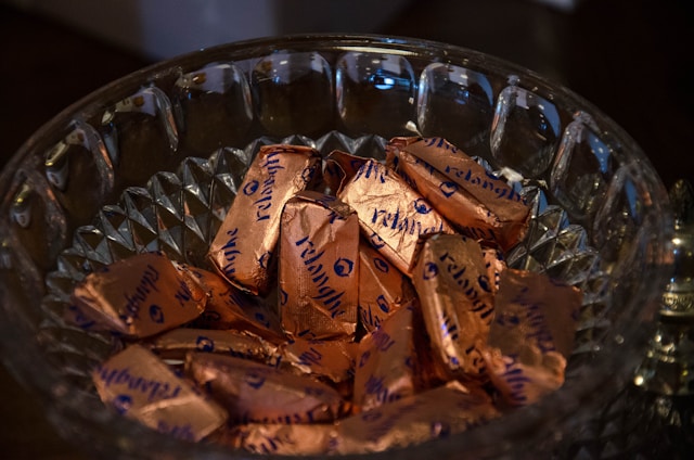 Glass bowl of wrapped chocolates in copper-coloured foil