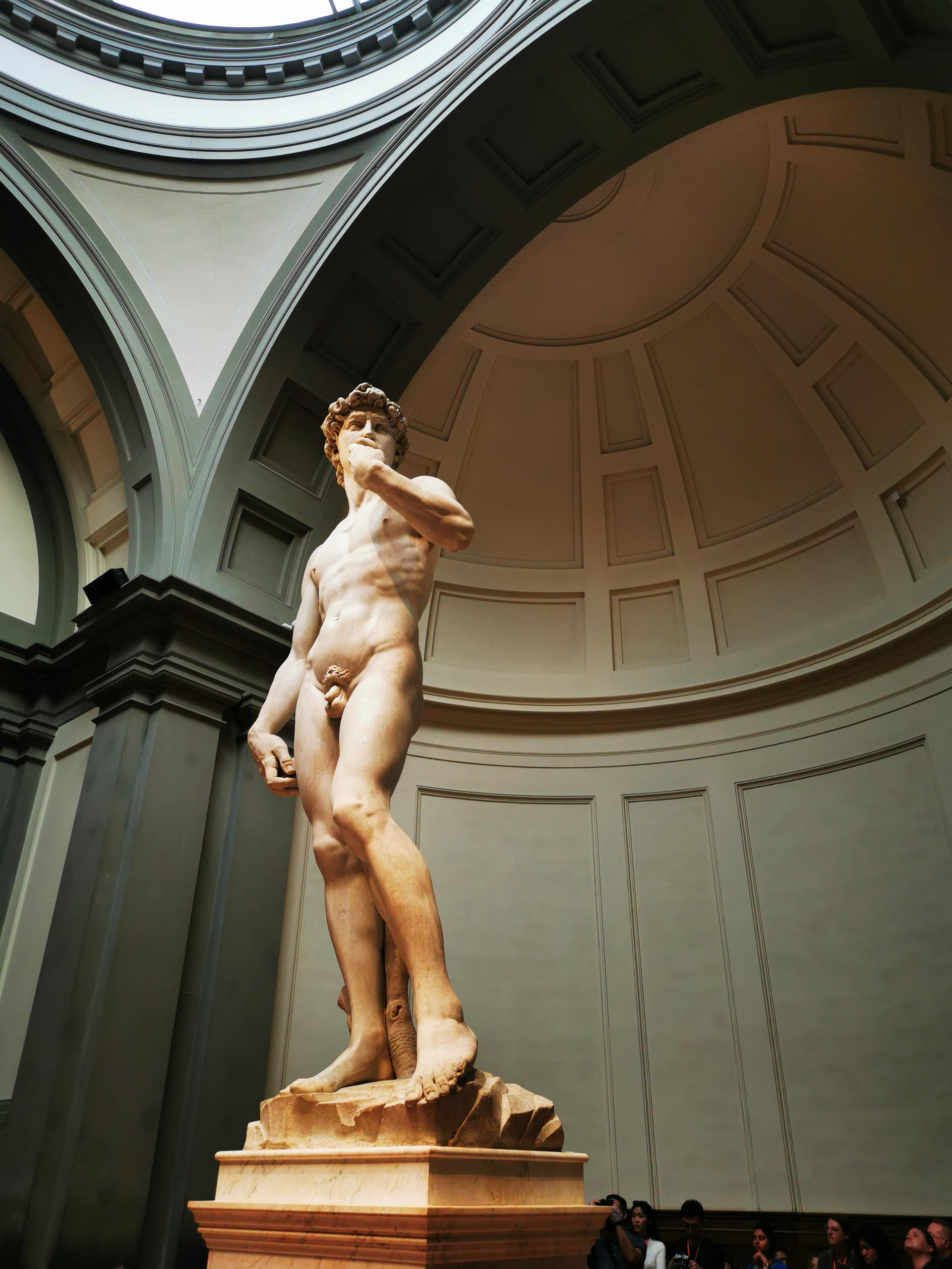 Michelangelo's David standing beneath a domed apse in the Accademia Gallery in Florence