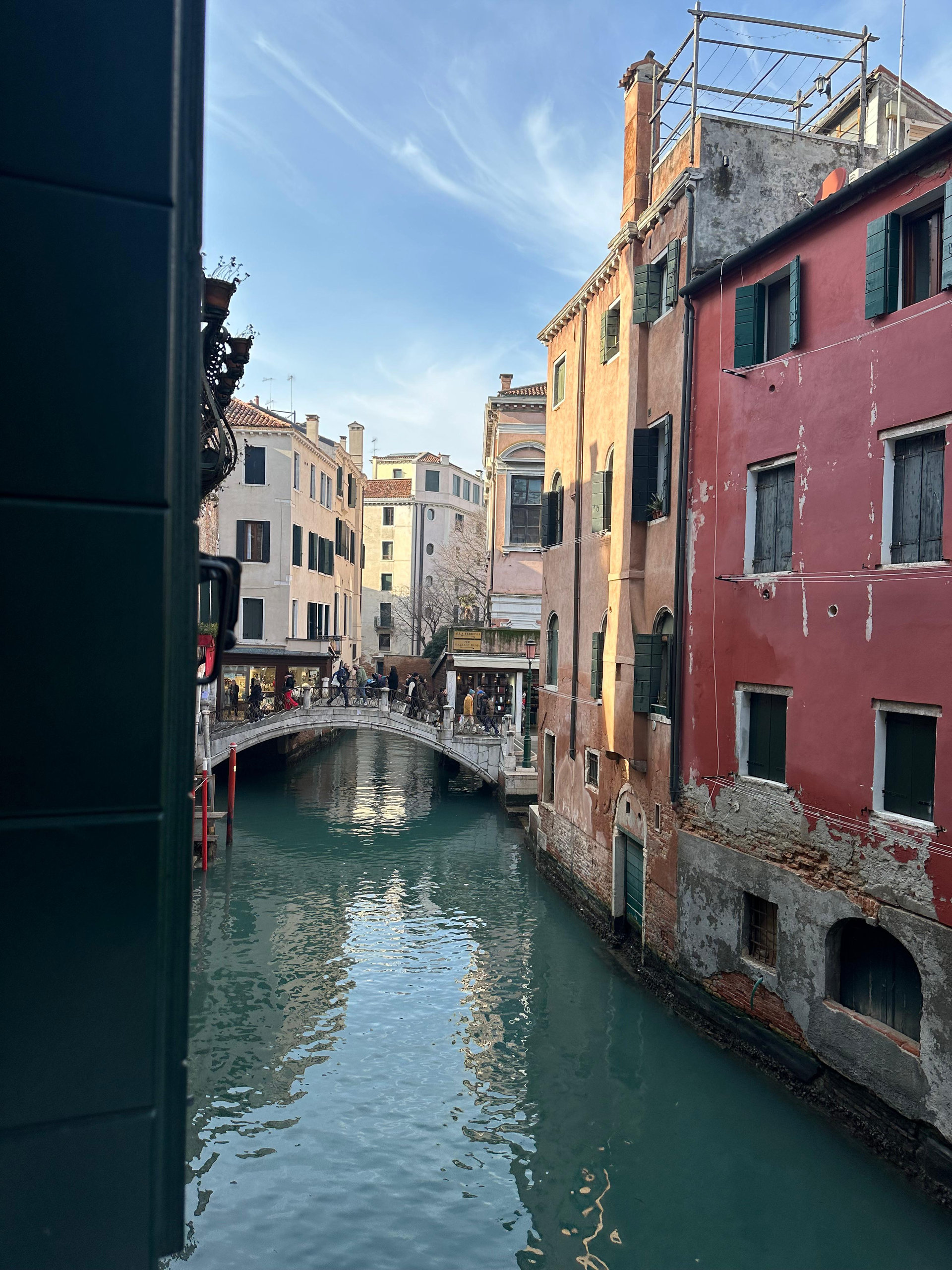 Venetian canal with a small footbridge between a red house and ochre buildings