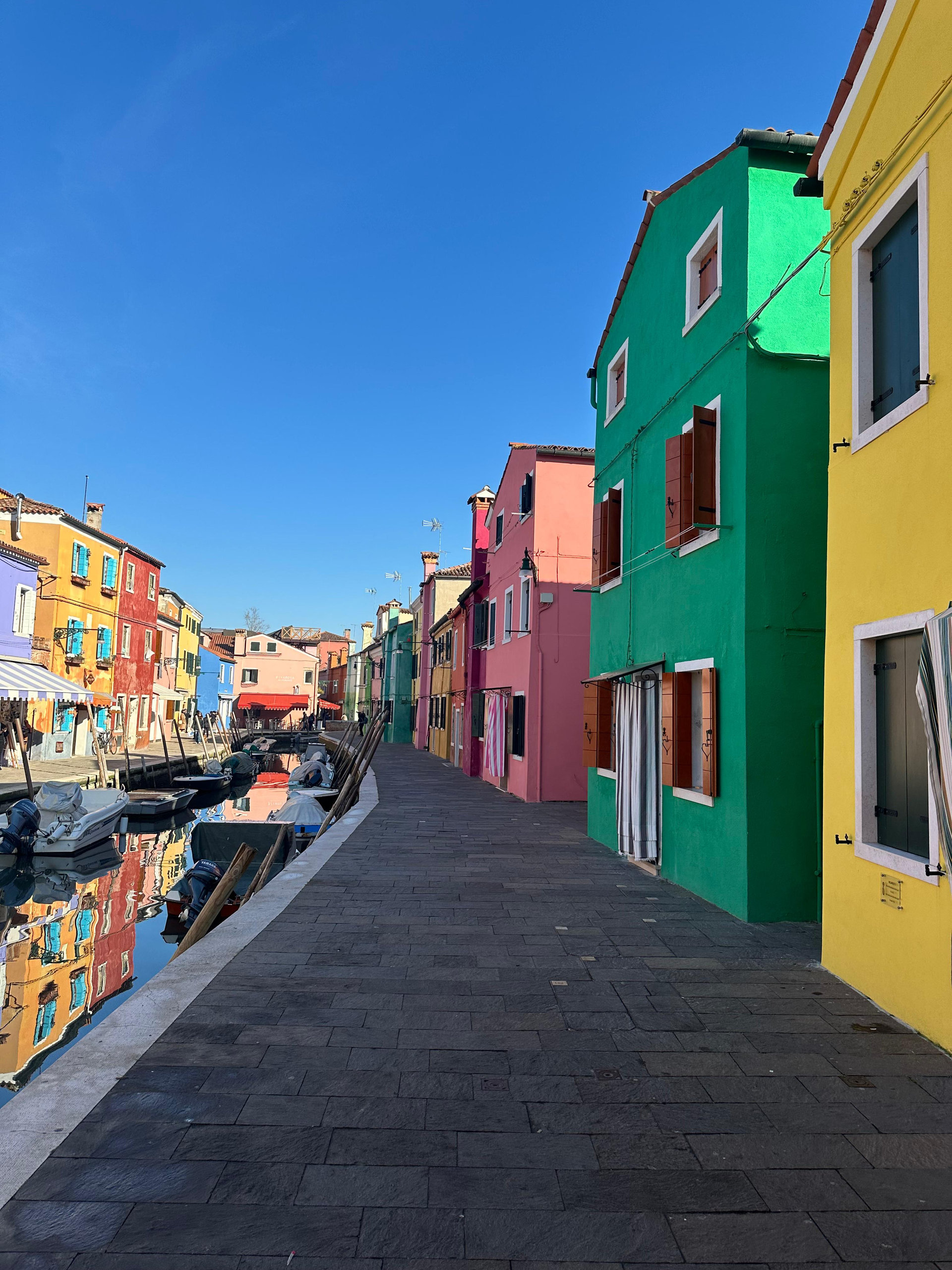 Brightly painted green, pink and yellow houses along a canal in Burano