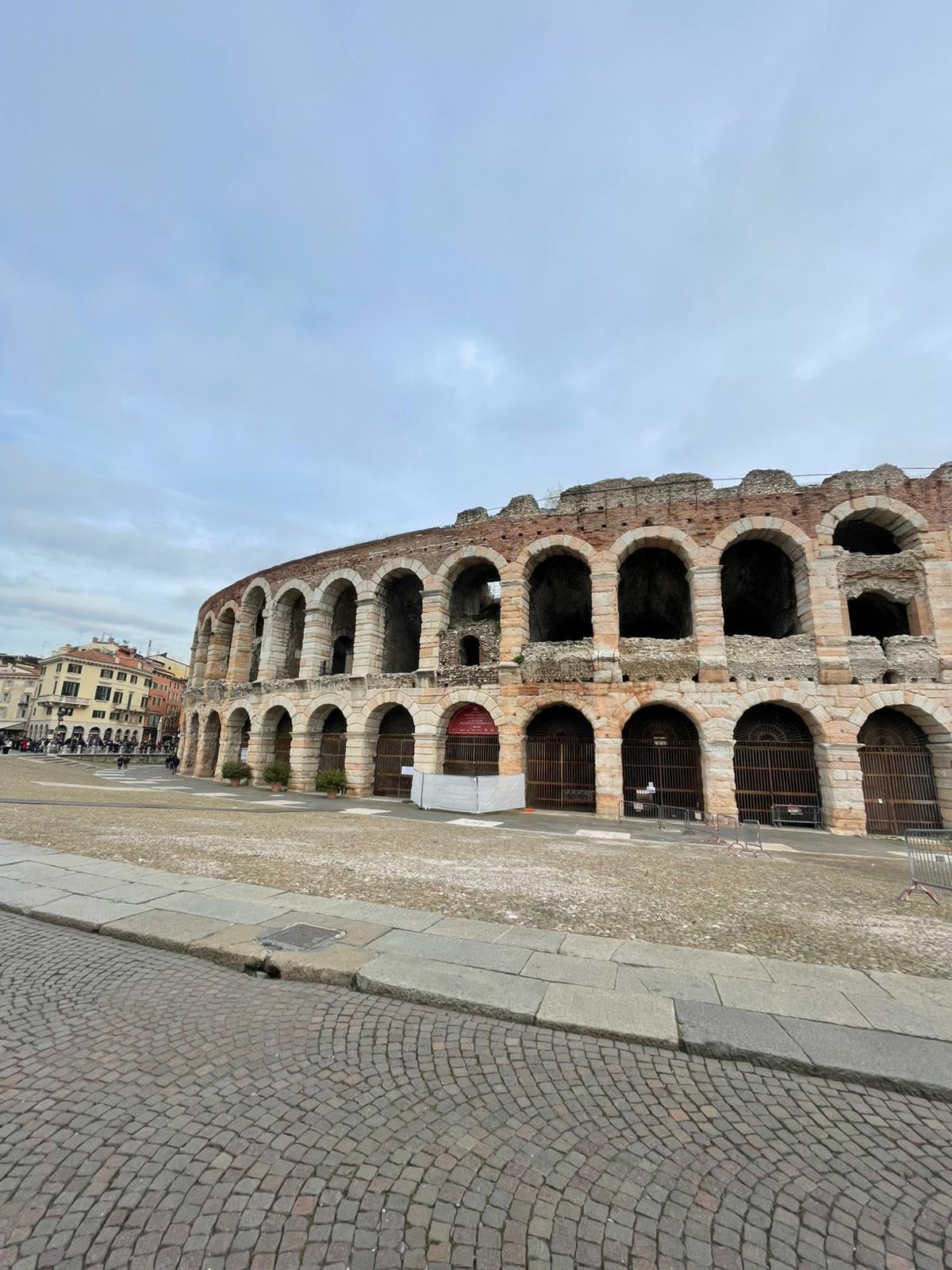 Roman amphitheatre with its tiered stone arches, seen from the cobbled square