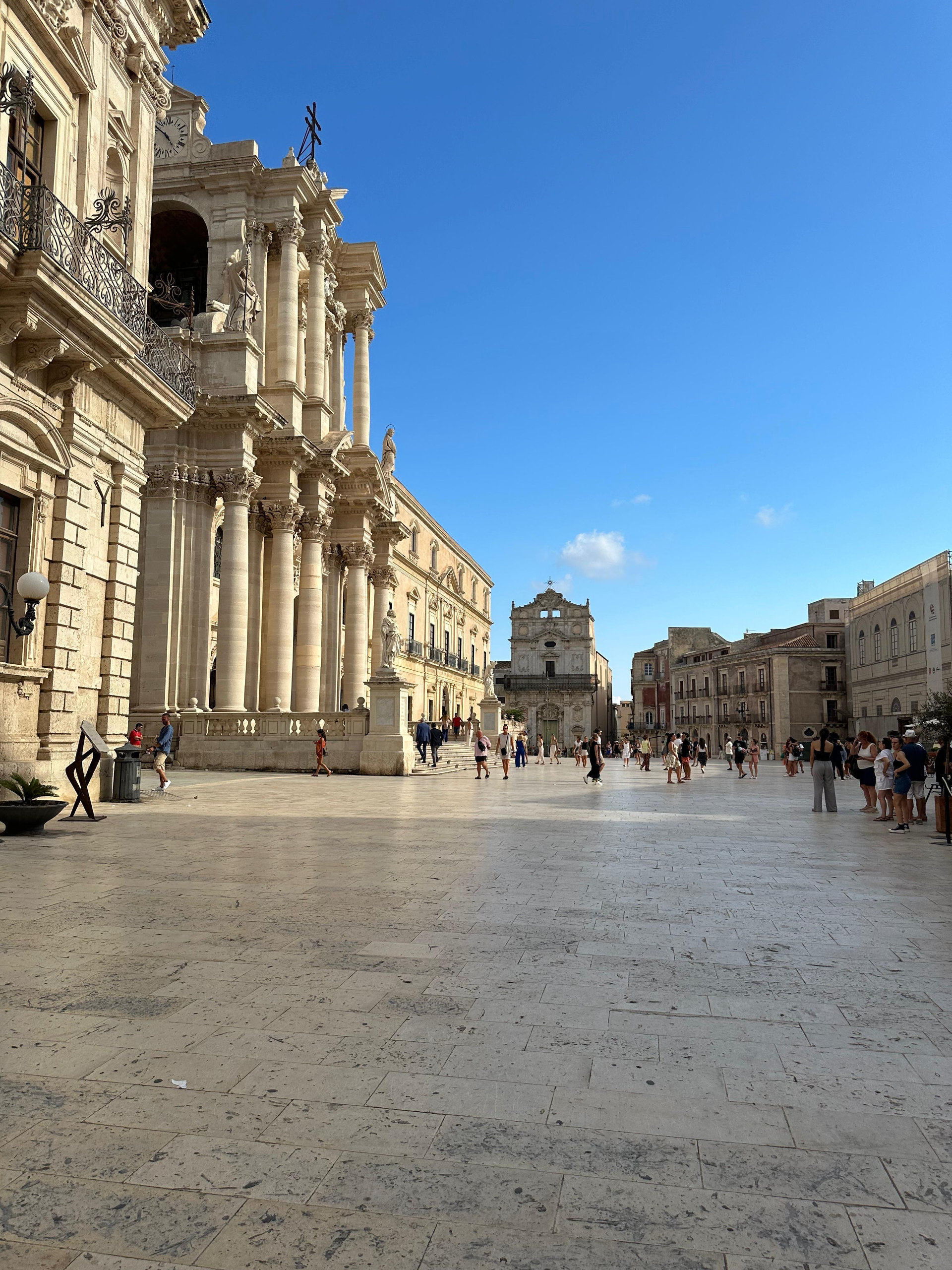 Sunlit cathedral square in Siracusa with a baroque facade and pale stone paving