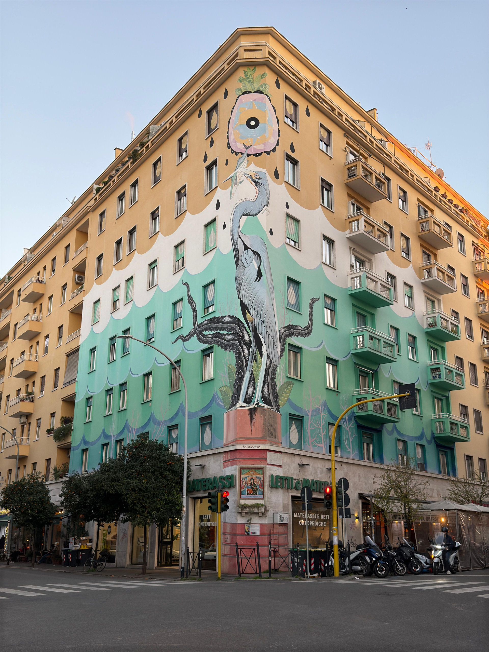 Corner apartment block painted with a large heron and waves in teal, white and ochre