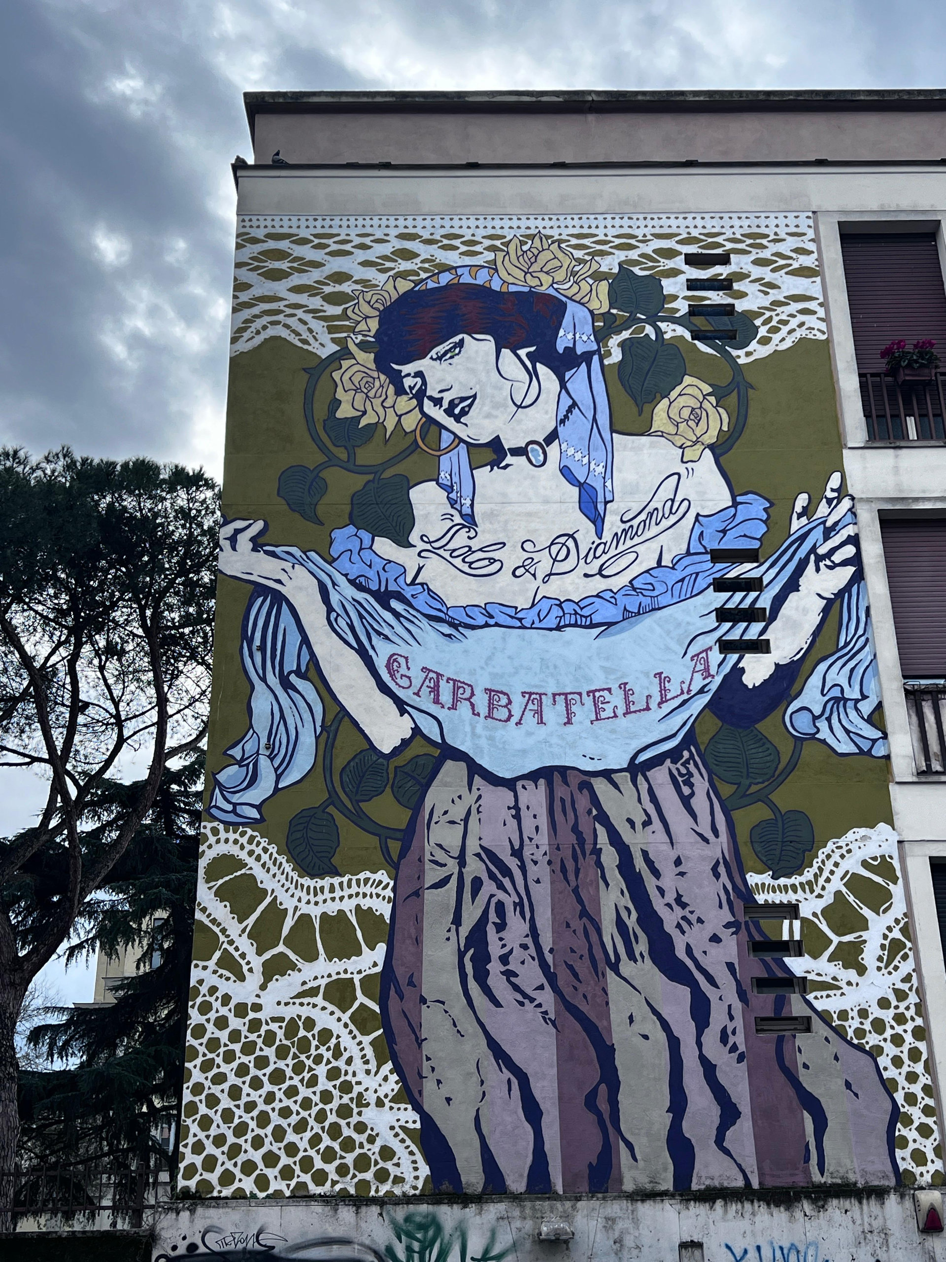 Mural of a woman in lace holding a banner reading 'Garbatella' on an apartment block