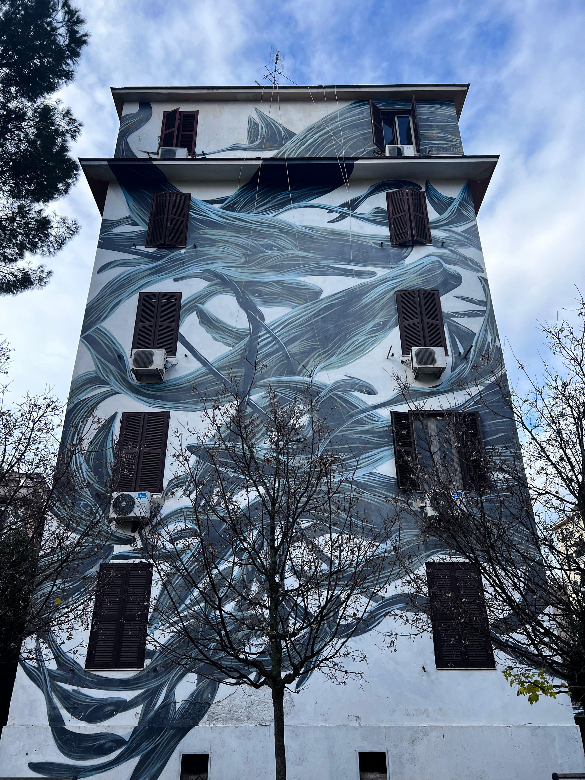 Flowing blue and grey mural of whales covering the facade of a residential block