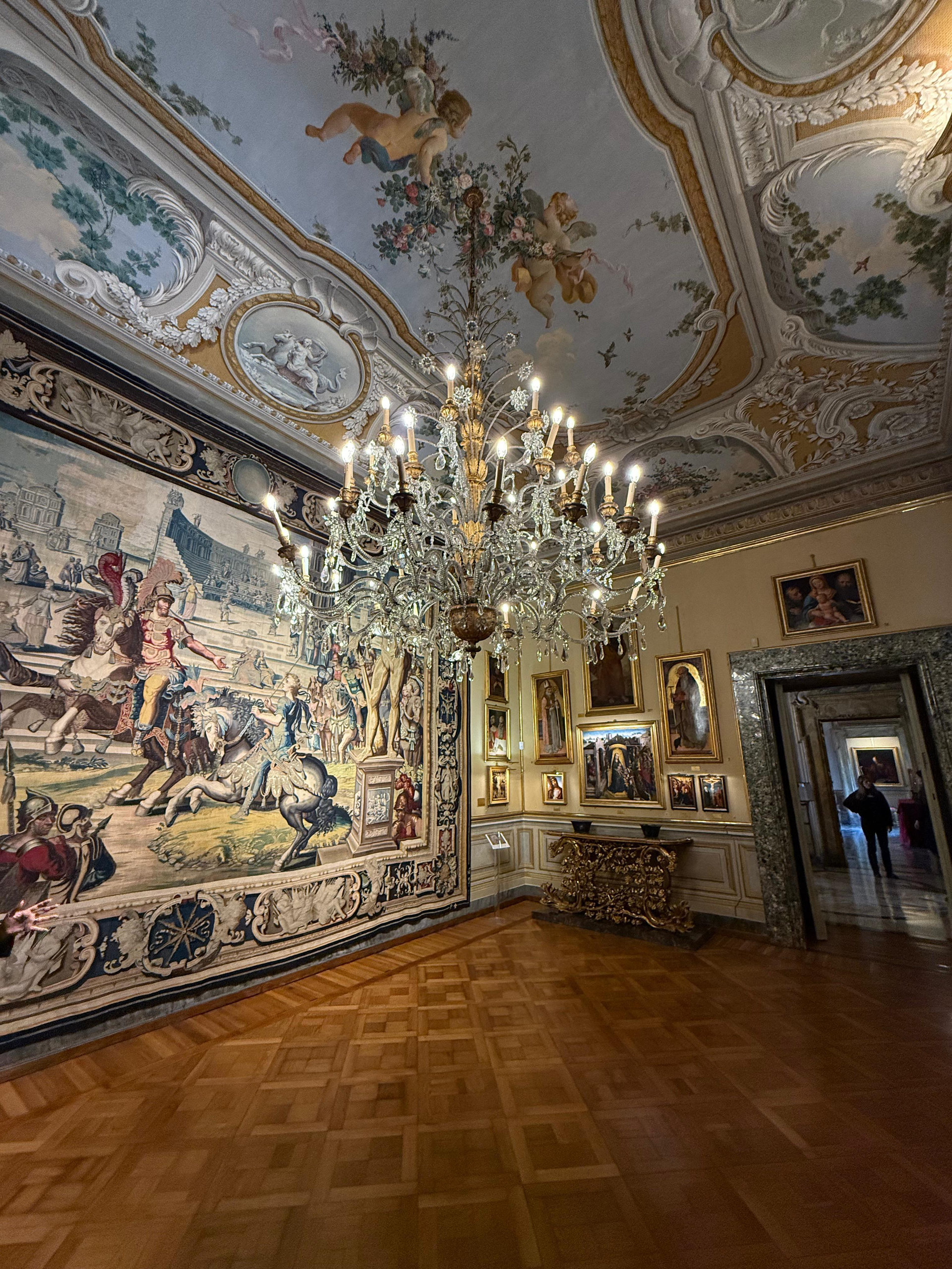 Palace room with a crystal chandelier, tapestry, painted ceiling and parquet floor