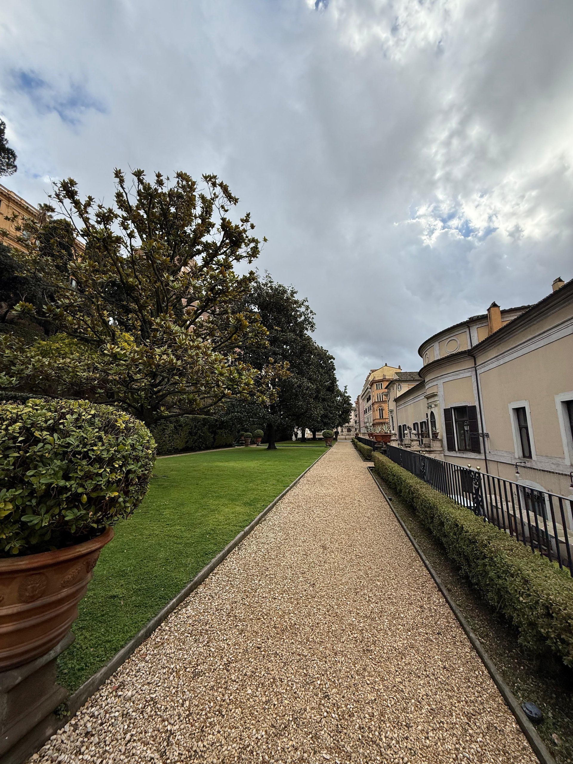 Gravel path beside a lawn and clipped hedges in the palace garden, with palace wing on the right