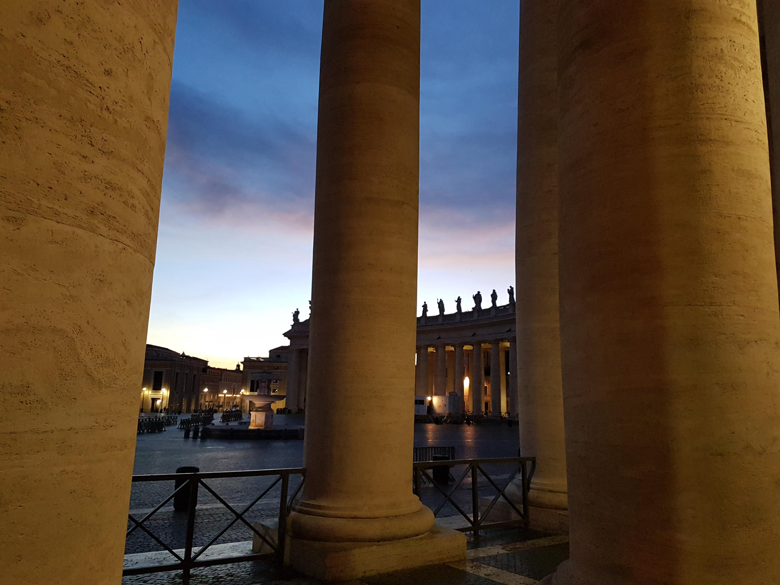 Travertine columns of the colonnade framing Saint Peter's Square at twilight