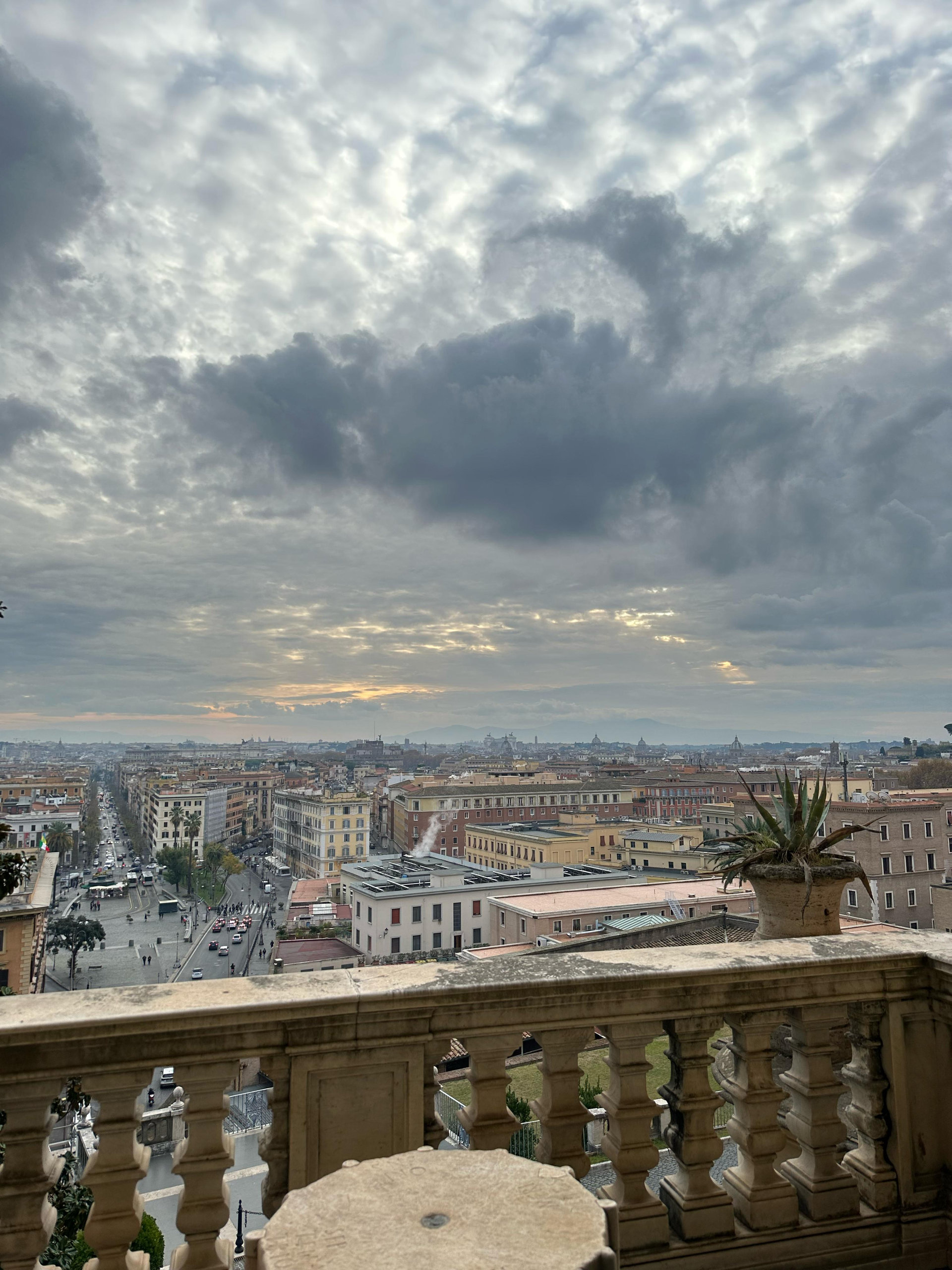 Balcony balustrade with a view over Rome's rooftops under dramatic clouds