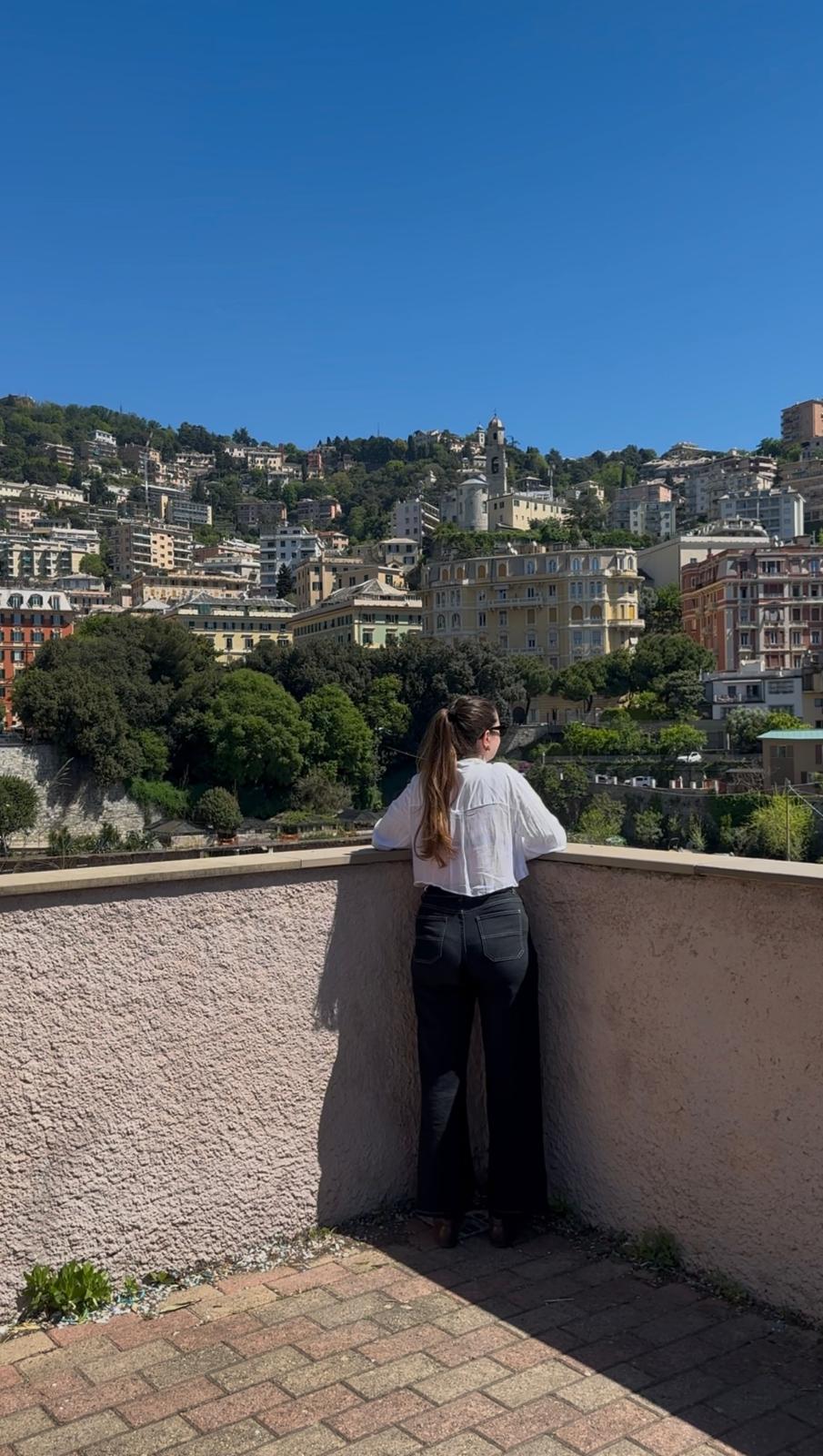 Traveller leaning on a terrace wall looking over pastel hillside houses