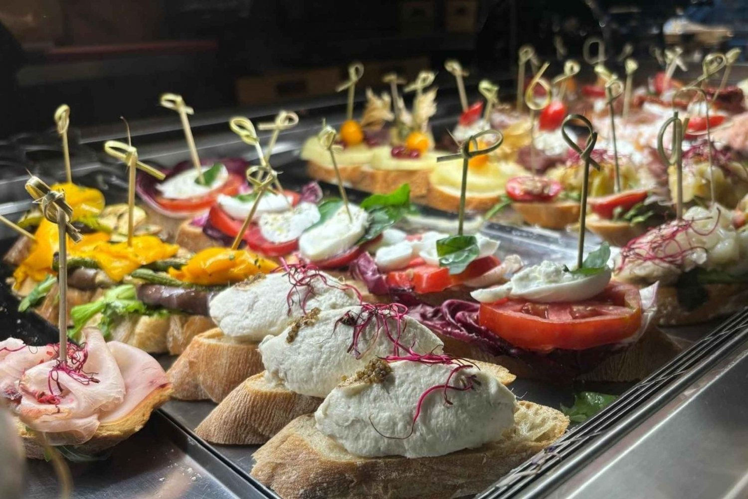 Display of Venetian cicchetti topped with creamy cheese, tomato and fresh herbs on slices of bread