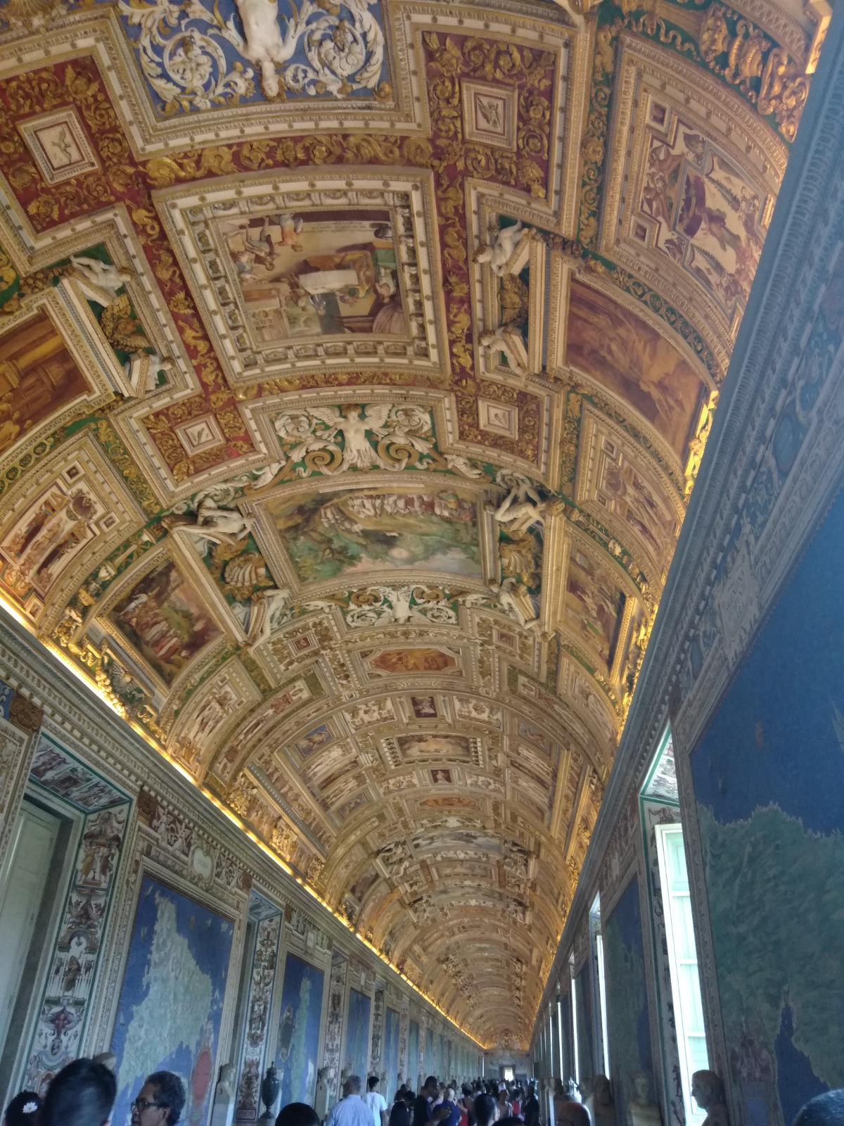 Gilded, frescoed vaulted ceiling of the Gallery of Maps in the Vatican Museums, with visitors below