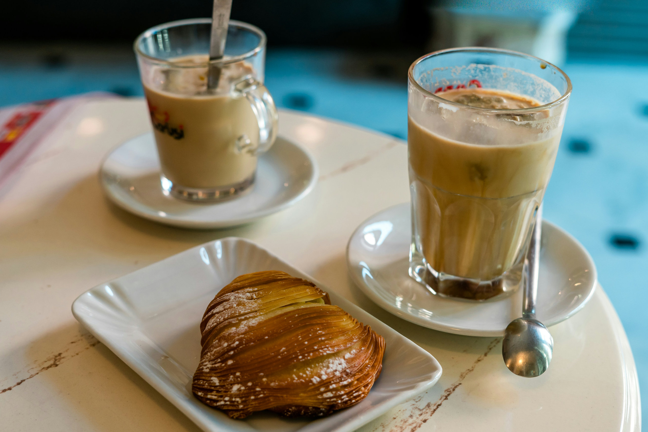 Sfogliatella pastry and two glasses of iced coffee on a marble café table