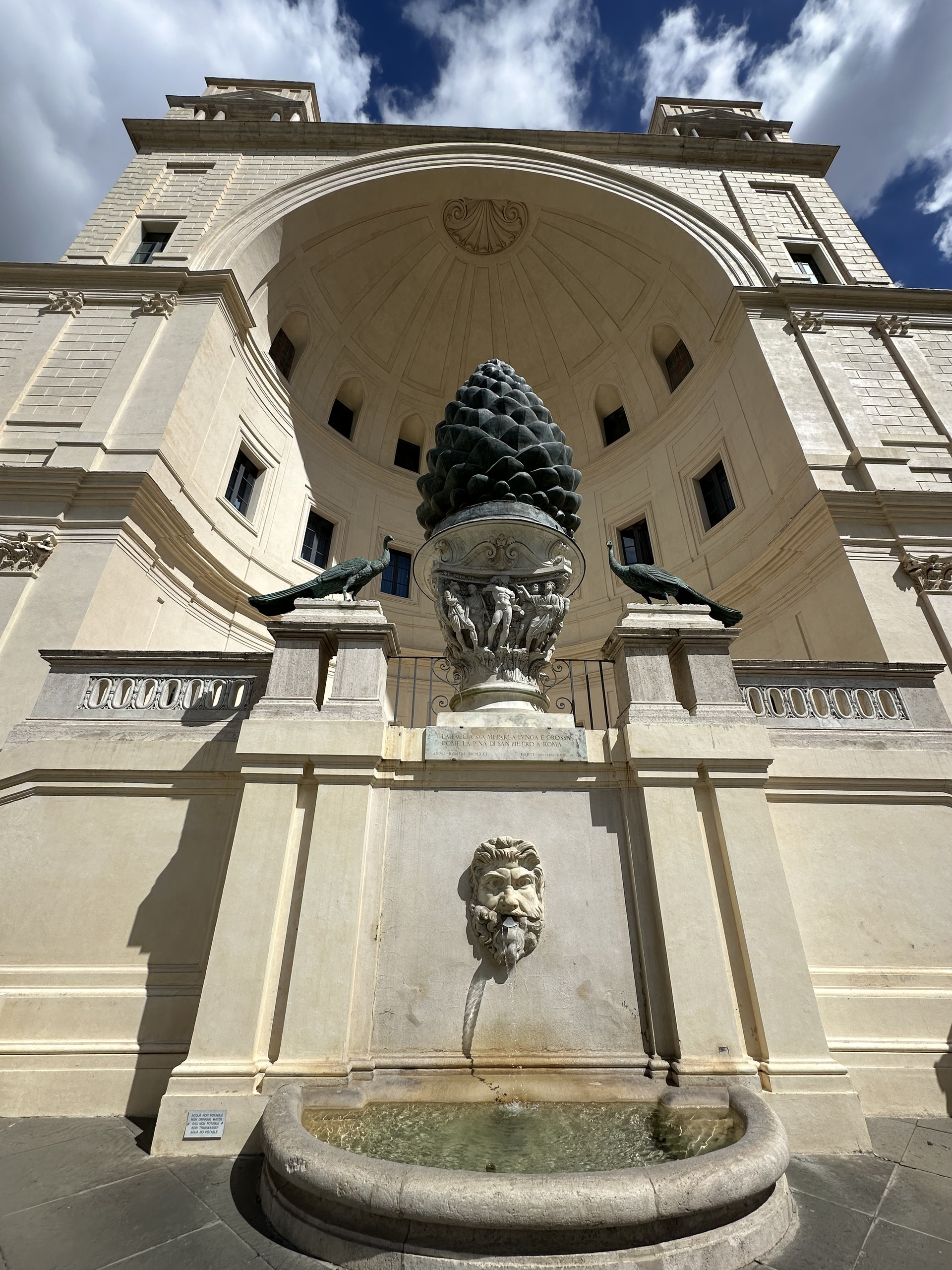 Bronze pine cone fountain in the Cortile della Pigna, with a stone mask fountain in the foreground