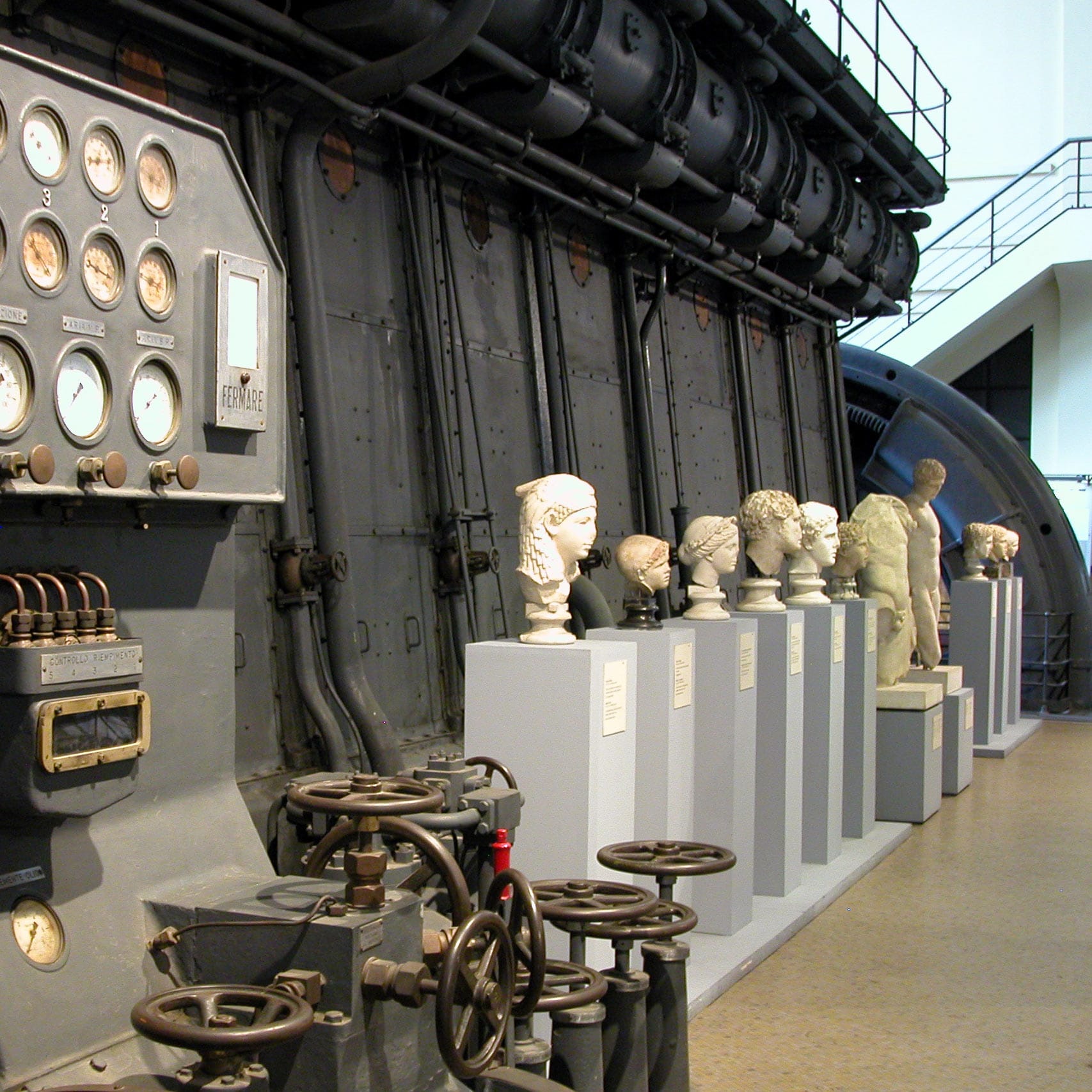 Row of ancient marble portrait busts on plinths beside a vintage control panel with dials and valve wheels