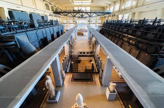 Overhead view of the former power station hall with classical statues between giant black machinery