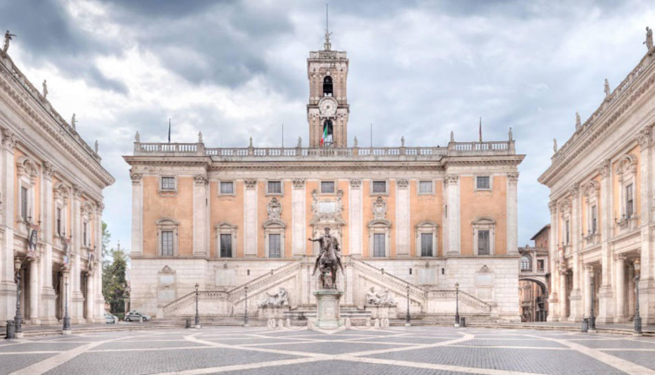 Piazza del Campidoglio with its ochre palazzo, clock tower and equestrian statue under a cloudy sky