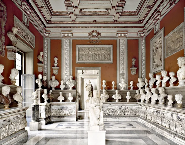 Hall of Roman busts and relief friezes against terracotta-red walls