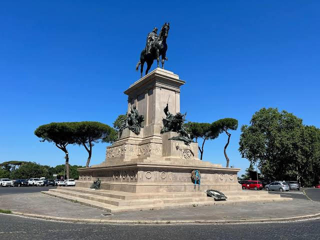 Bronze equestrian monument on a stepped stone base, framed by umbrella pines on the Janiculum Hill